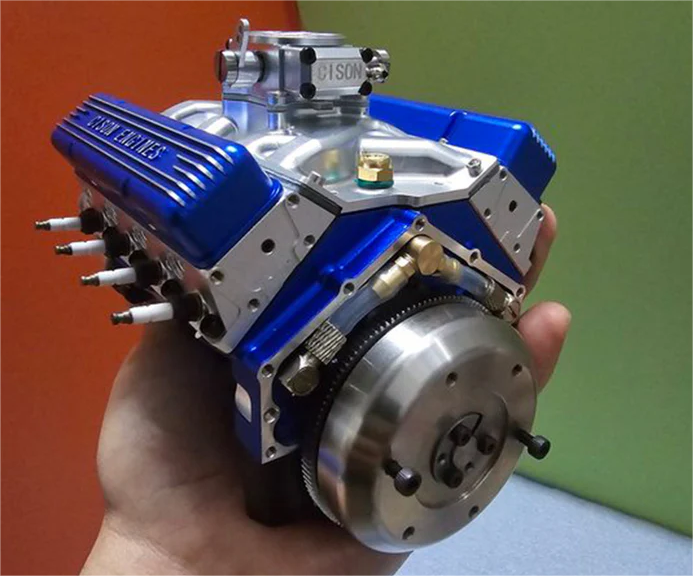 A hand holding a V8 engine model kit.